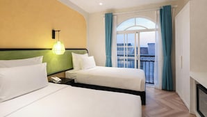 A hotel room with two beds, a nightstand with a phone, a lamp, and a view of the city through a large window with curtains. - HAN Sunset Milan Hotel & Spa (Phu Quoc)