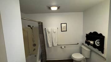A bathroom with a shower, toilet, and a towel rack.