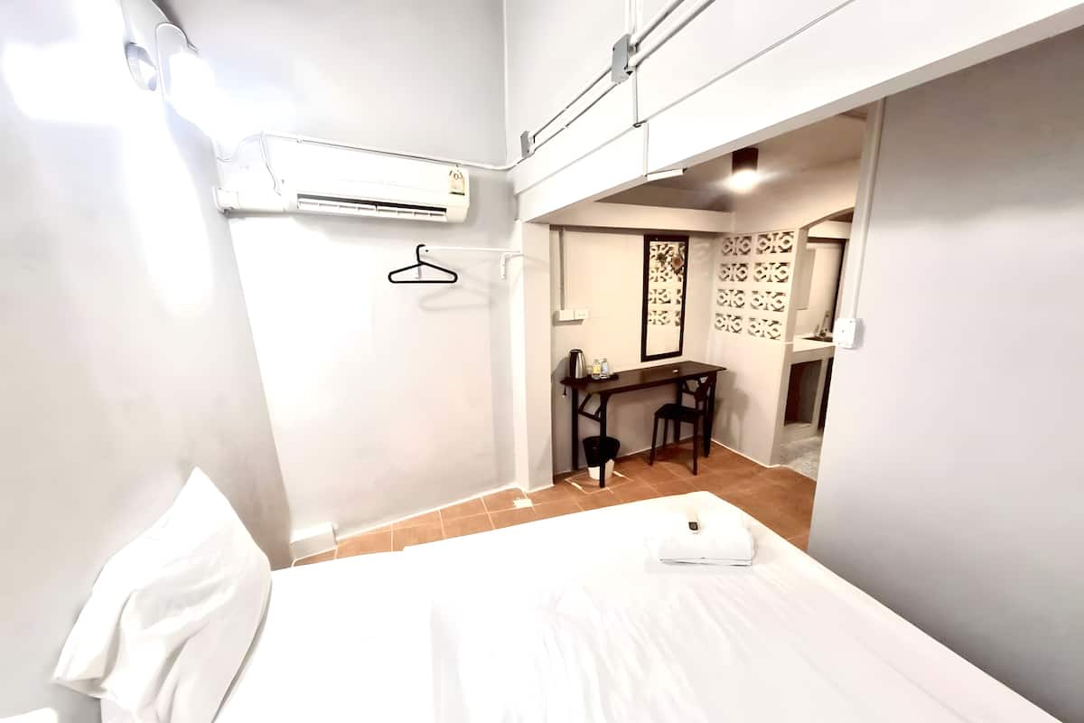 Habitación de hotel con una cama, un escritorio y un aire acondicionado.