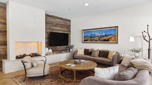 A living room with a fireplace, a sofa set, a coffee table, and a mounted TV. - Misty Maiden Lodge by Avantstay Prime Ski-in Ski-out Retreat + Hot Tub + Steps to Lift & Gondola (Telluride)