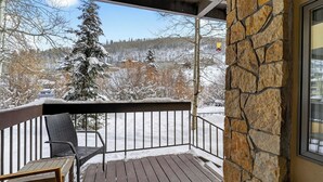 A wooden deck with a stone wall, a metal railing, and a chair. - Misty Maiden Lodge by Avantstay Prime Ski-in Ski-out Retreat + Hot Tub + Steps to Lift & Gondola (Telluride)