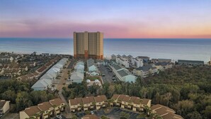A coastal hotel with multiple-story buildings, a parking lot, and a view of the ocean. - Beachwalk 10B by Avantstay PCB Condo Across From the Beach + Pool & Tennis Court (Panama City Beach)