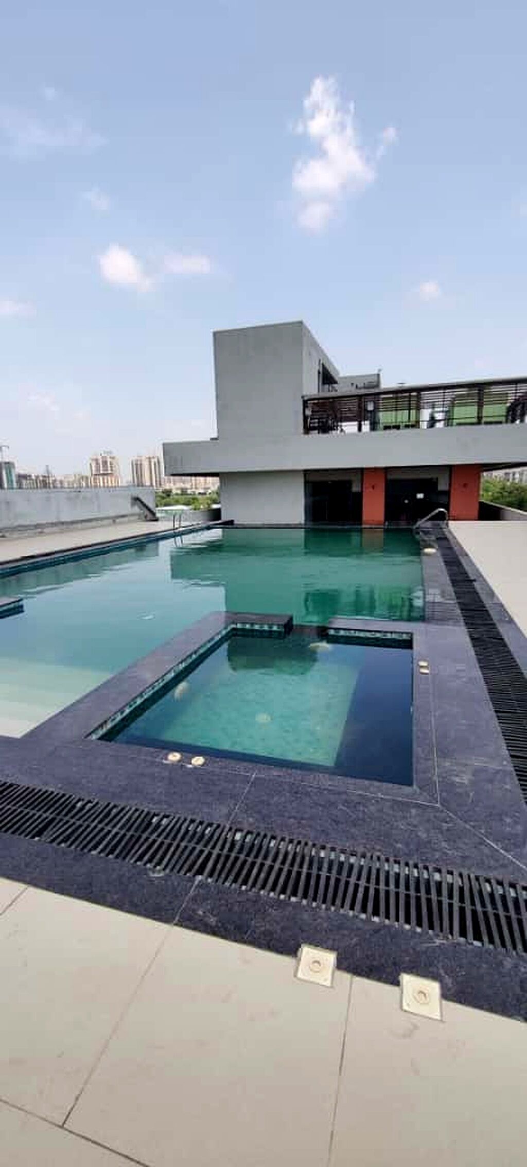 A rooftop swimming pool with a modern building in the background.