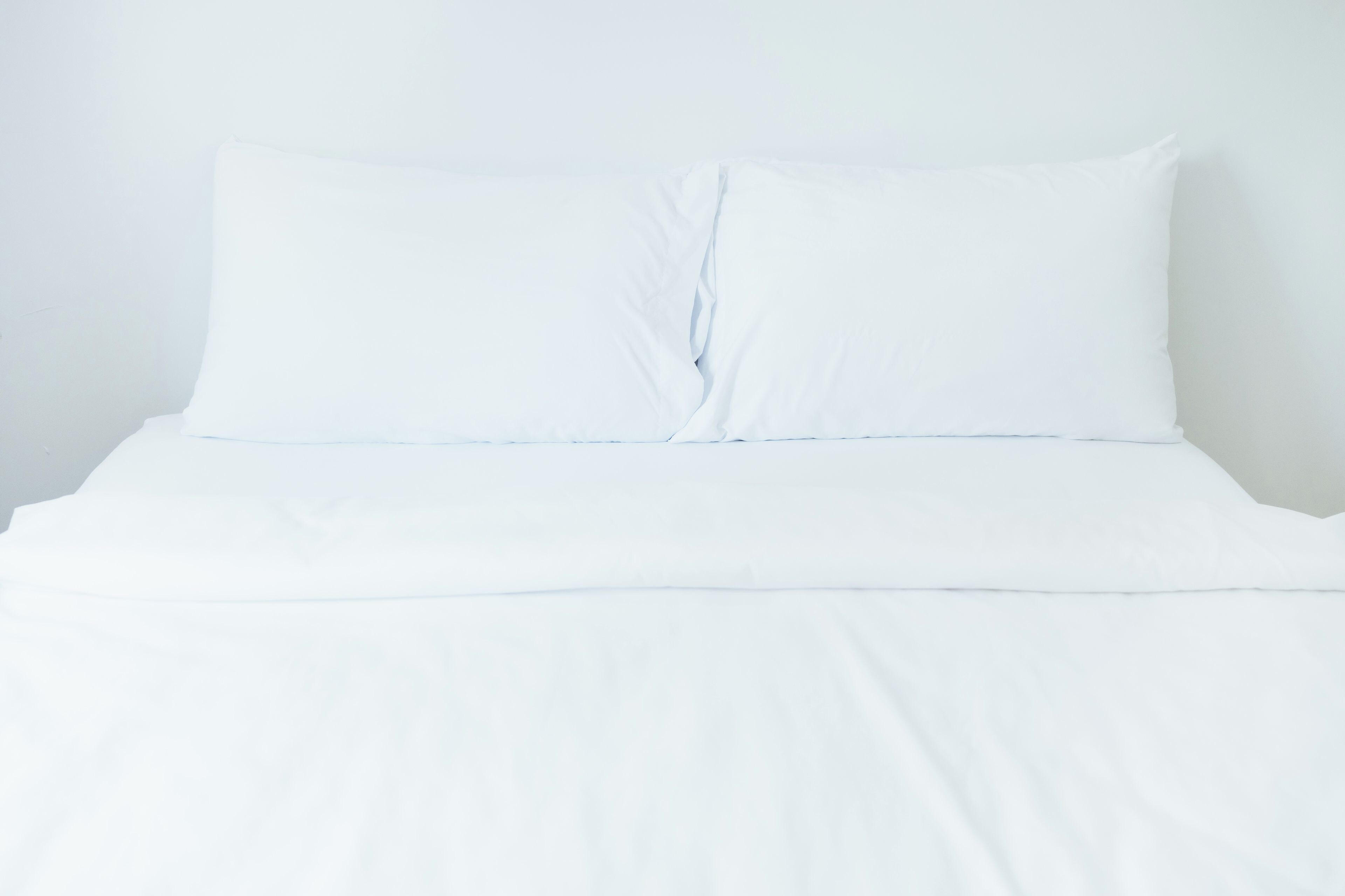 A bed with white bedding and a pillow.