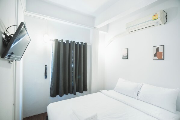 A hotel room with a bed, a flat-screen TV, a window with curtains, and an air conditioning unit. - Sleep Pop CMU Chiang Mai (Chiang Mai)