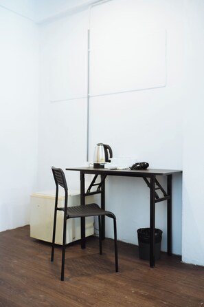 A small, dark-colored desk with a chair, a trash bin, and a white wall. - Sleep Pop CMU Chiang Mai (Chiang Mai)