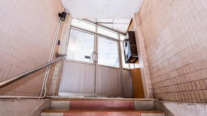 Un escalier menant à une porte dotée d’une rampe métallique et d’un panneau de verre.