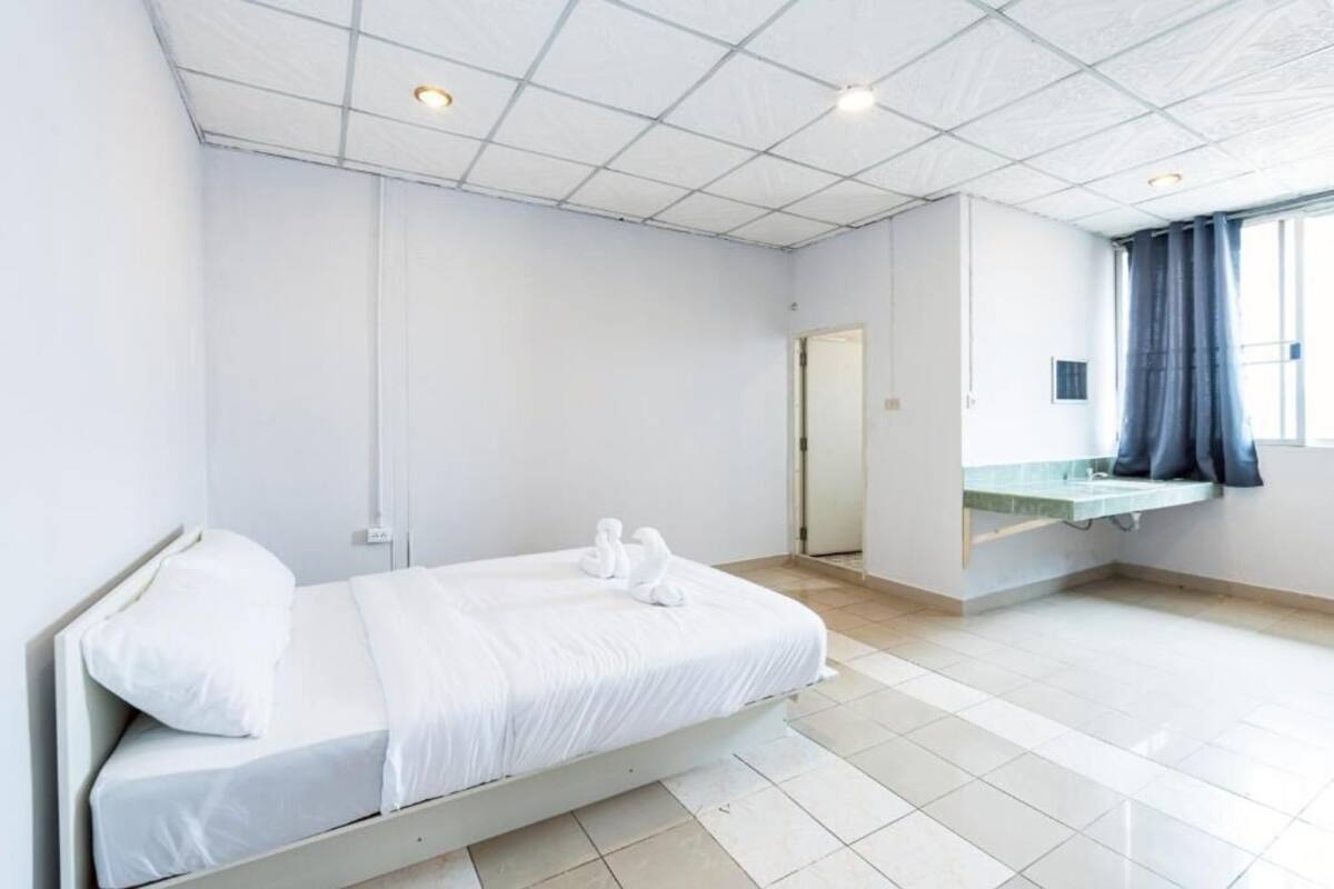 Une chambre d’hôtel propre et moderne, dotée d’un lit, d’une coiffeuse intégrée avec un miroir et d’une fenêtre avec des rideaux.