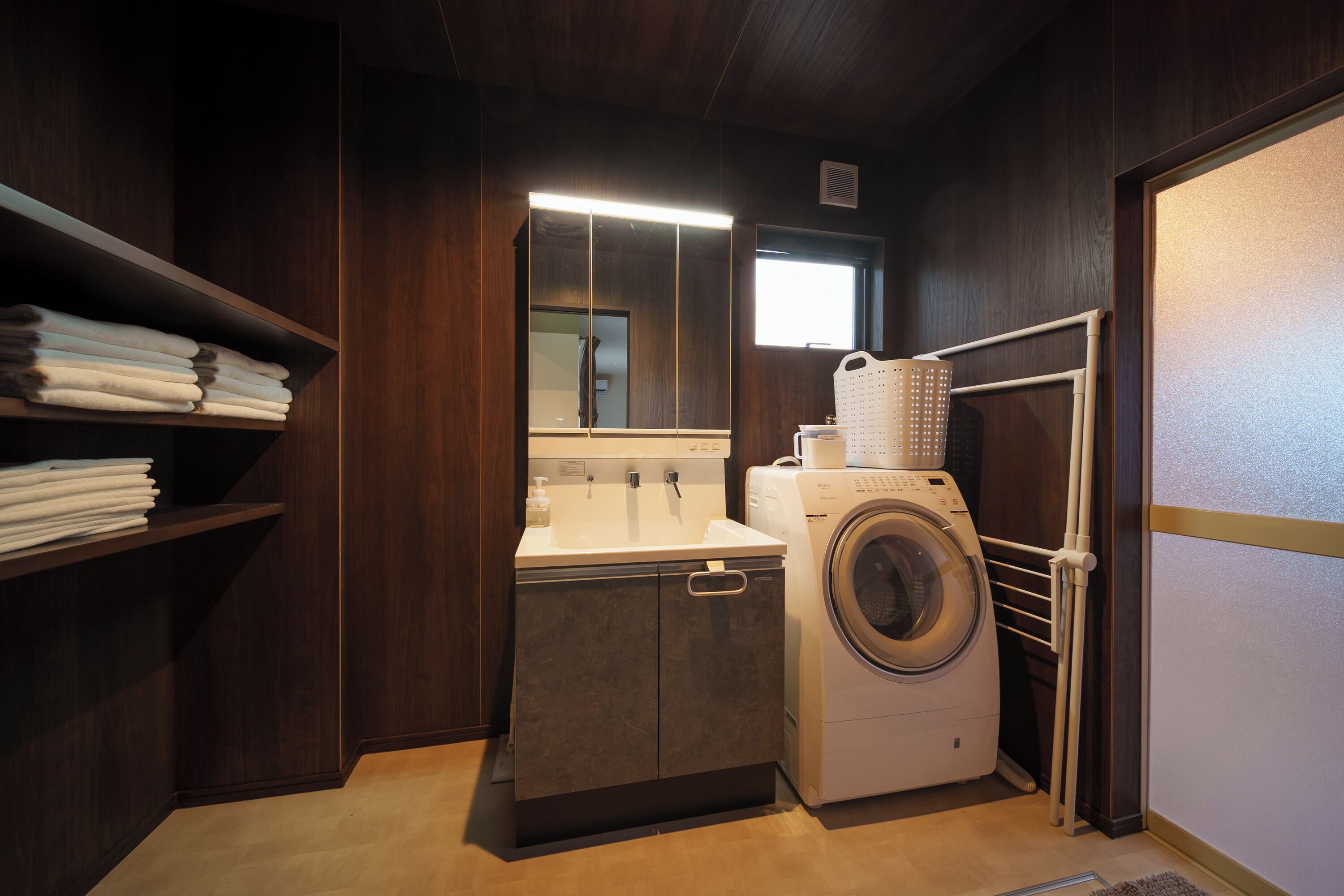 A compact laundry room with a washing machine, a sink, and a mirror.