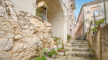 A narrow stone staircase in a historic building with potted plants and outdoor seating.