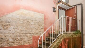 A stone staircase with a metal railing leading to a wooden door.