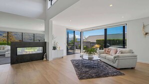 A spacious living room with a fireplace, a sofa, and a coffee table. - Diamond on the Peninsula (Wānaka)