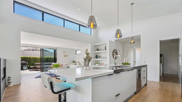 A modern kitchen with a large island, pendant lighting, and a view of the outdoors. - Diamond on the Peninsula (Wānaka)