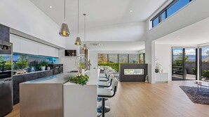 A modern kitchen with a central island, bar seating, and a fireplace. - Diamond on the Peninsula (Wānaka)