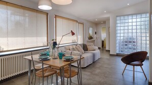 Un salon moderne avec un coin repas, de grandes fenêtres et une vue sur la ville.