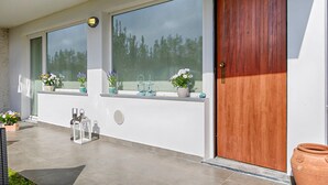 Une façade moderne avec de grandes fenêtres, une porte en bois et des plantes en pot sur le rebord de la fenêtre.