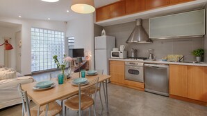 Une cuisine moderne dotée de meubles en bois, d’appareils électroménagers en acier inoxydable et d’un coin repas avec une table et des chaises.