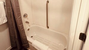 A bathroom with a white bathtub, a shower curtain, and a towel rack. - Wedding and Party Venue (Challenge-Brownsville)