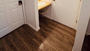 A bathroom with a wooden floor, a white door, and a wooden countertop with a sink. - Wedding and Party Venue (Challenge-Brownsville)