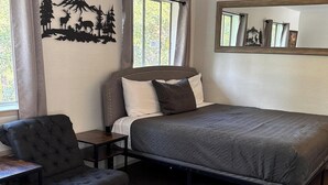 A neatly arranged bedroom with a bed, a chair, and a nightstand. - Wedding and Party Venue (Challenge-Brownsville)