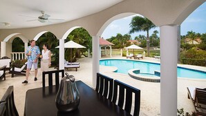 A covered outdoor area with a pool, lounge chairs, and umbrellas. - The Crown Oasis Luxury Escape All Inclusive (Puerto Plata)