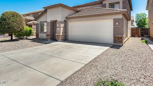 A two-story house with a garage, a driveway, and a well-maintained lawn. - Spacious 4BR w/ Backyard Spa Near Westgate Az (Youngtown)