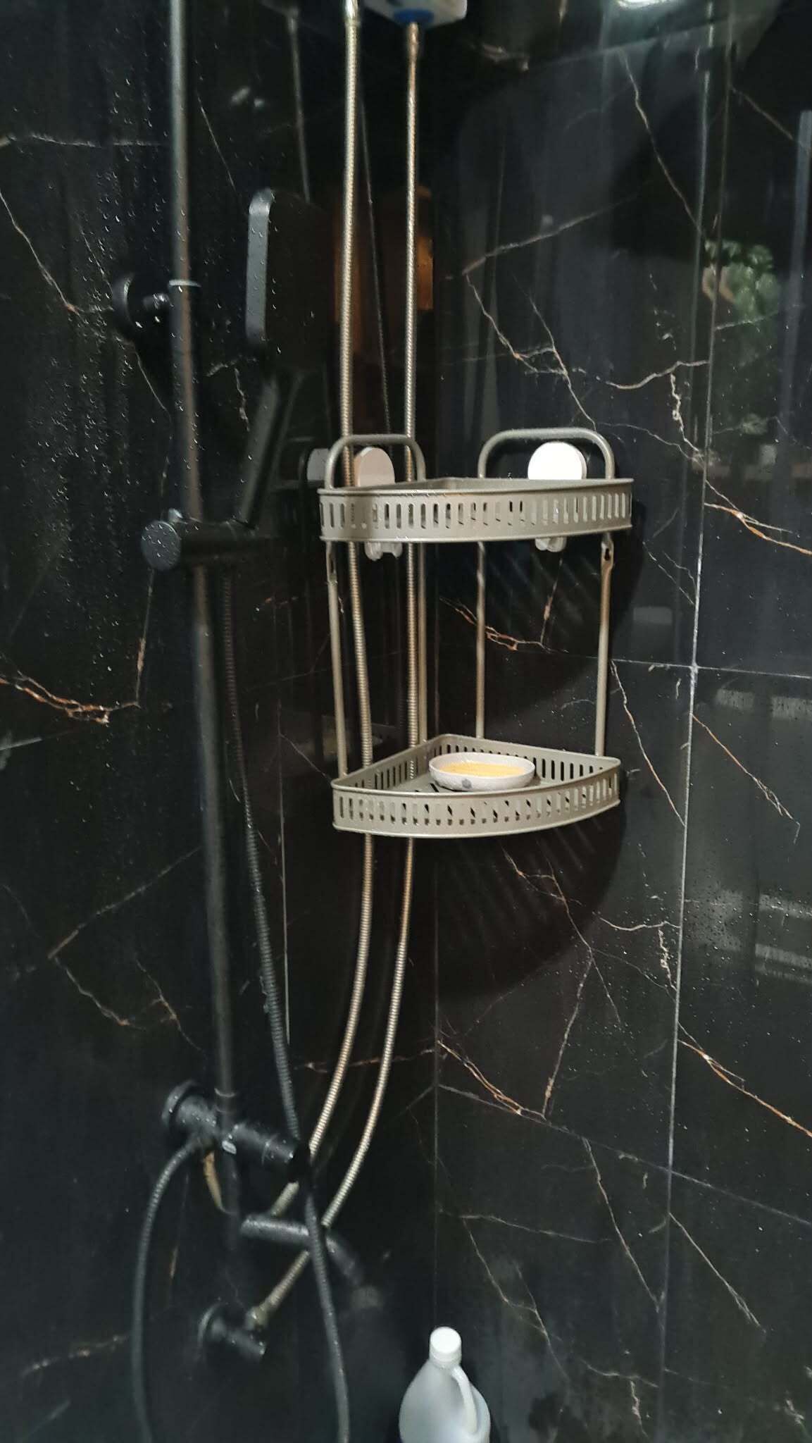 A shower with a metal rack holding a soap dish and a handheld showerhead.