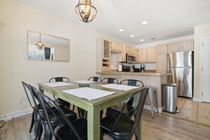 A modern kitchen with wooden cabinets, a stainless steel refrigerator, and a dining area with a table and chairs. - Powder & Paddle at Lake Harmony (Lake Harmony)