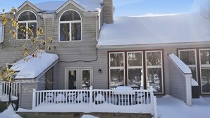 Une maison à deux étages, dont le toit est recouvert de neige, et qui possède un porche avec une balustrade blanche.