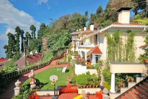 Una propiedad en una ladera con jardines escalonados, una cancha de baloncesto y una variedad de plantas en macetas.