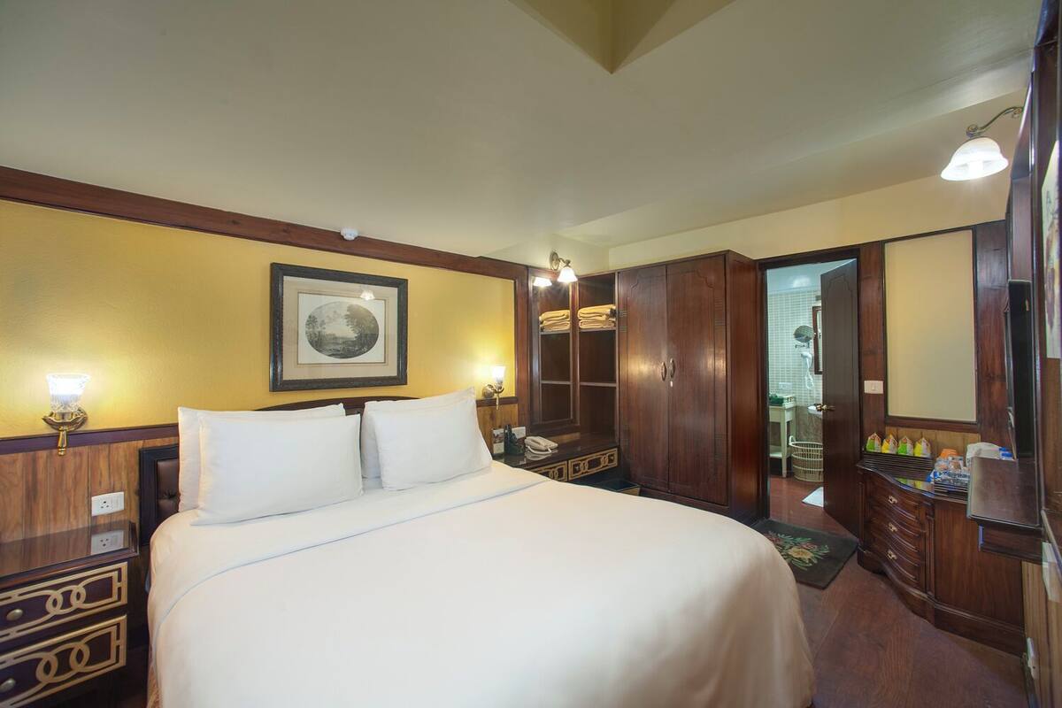 Een hotelkamer met een groot bed, een houten garderobe en een lijst met een afbeelding aan de muur.