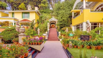 A pathway leading to a building surrounded by lush greenery and potted plants.