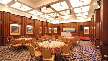 A conference room with round tables, chairs, and a stage.