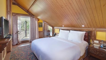 A spacious bedroom with a large bed, wooden ceiling, and a balcony with curtains.