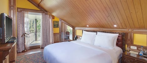A spacious bedroom with a large bed, wooden ceiling, and a balcony with curtains.