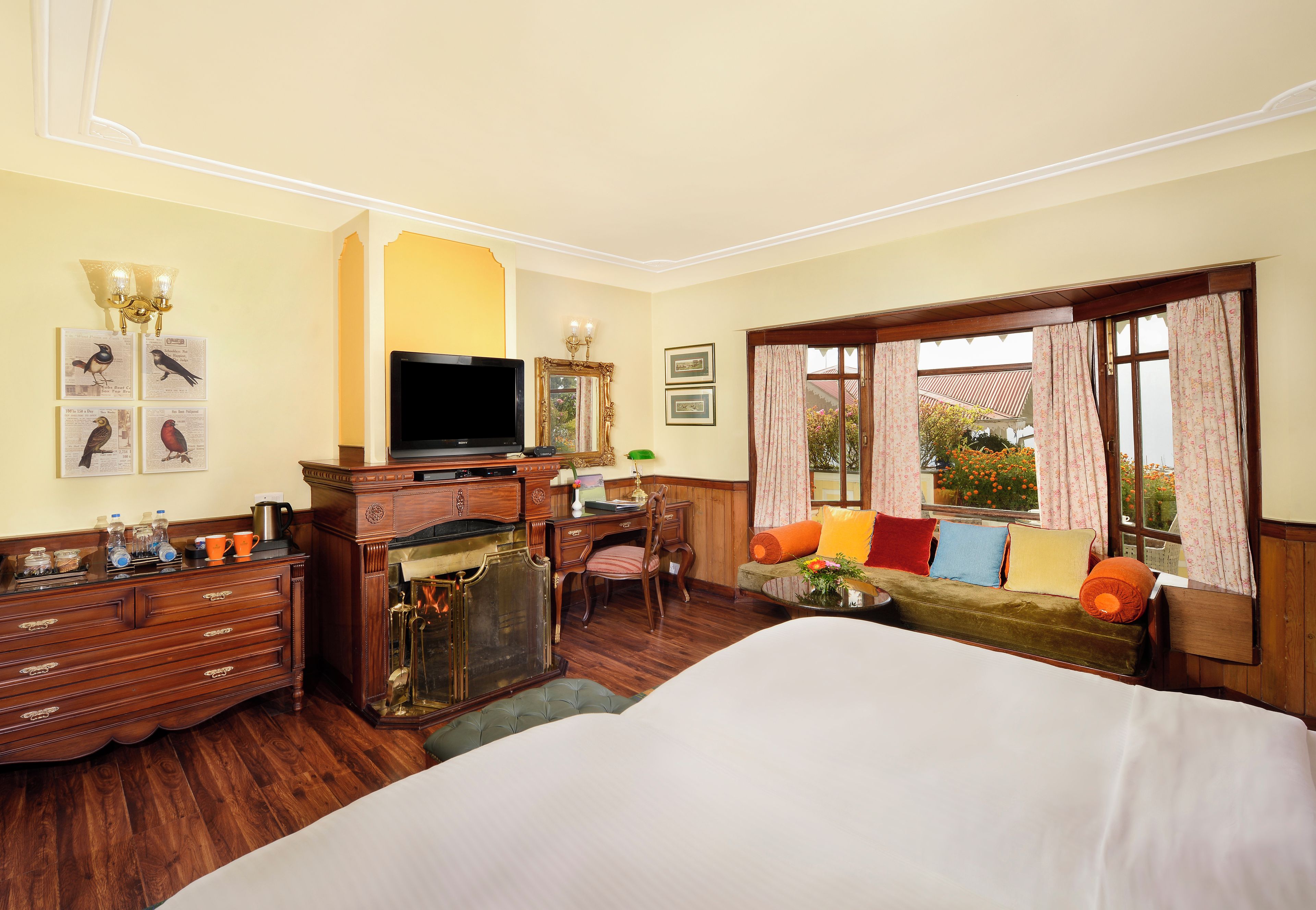A hotel room with a bed, a desk with a computer, a television, and a window with curtains.