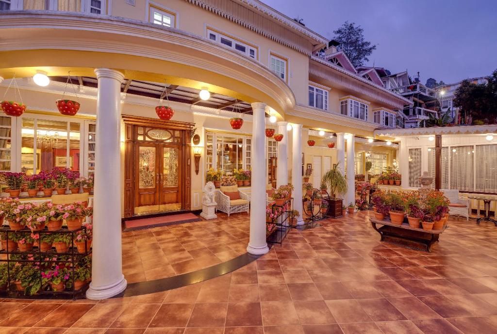 A hotel with a spacious courtyard, multiple columns, and a variety of potted plants.