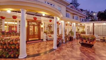 A hotel with a spacious courtyard, multiple columns, and a variety of potted plants.