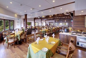 Un comedor amplio con varias mesas dispuestas para los huéspedes, con una isla central que tiene una cafetera y vistas al exterior.