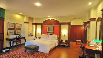 A hotel room with a large bed, a desk, a chair, a desk lamp, and a telephone.