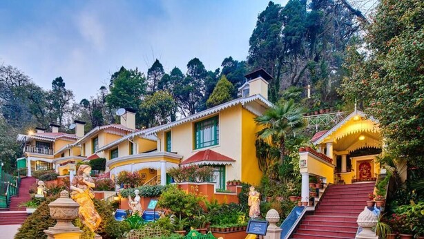 Um hotel com vários edifícios amarelos, um parquinho e estátuas.