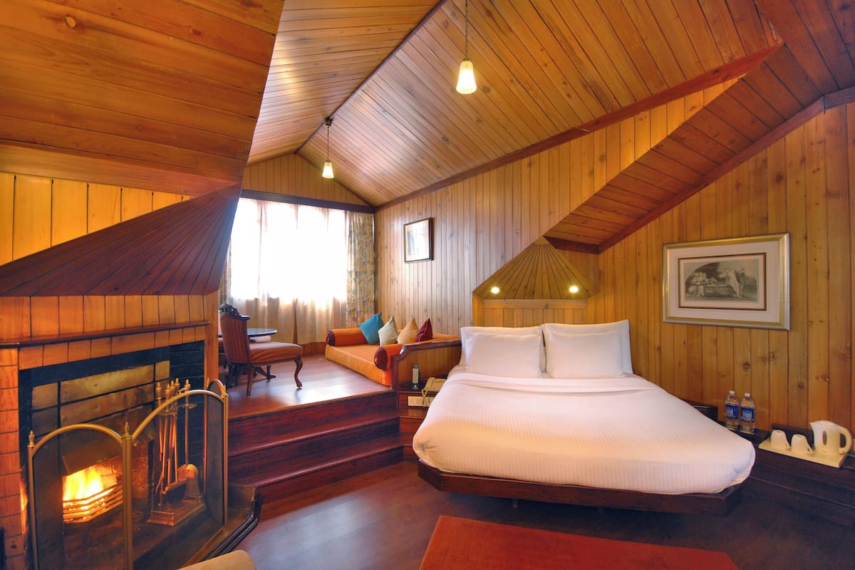 Een knus slaapkamer met een open haard, een groot bed en een trap naar een verdieping.