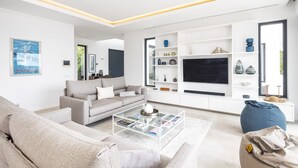 Ein modernes Wohnzimmer mit einer Couch, einem Couchtisch und einem Fernseher an einer weißen Wand.
