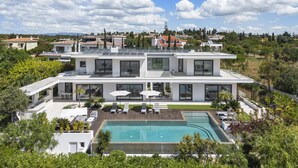 Ein modernes, zweistöckiges Haus mit Swimmingpool, Solaranlage und Blick auf die umliegende Landschaft.