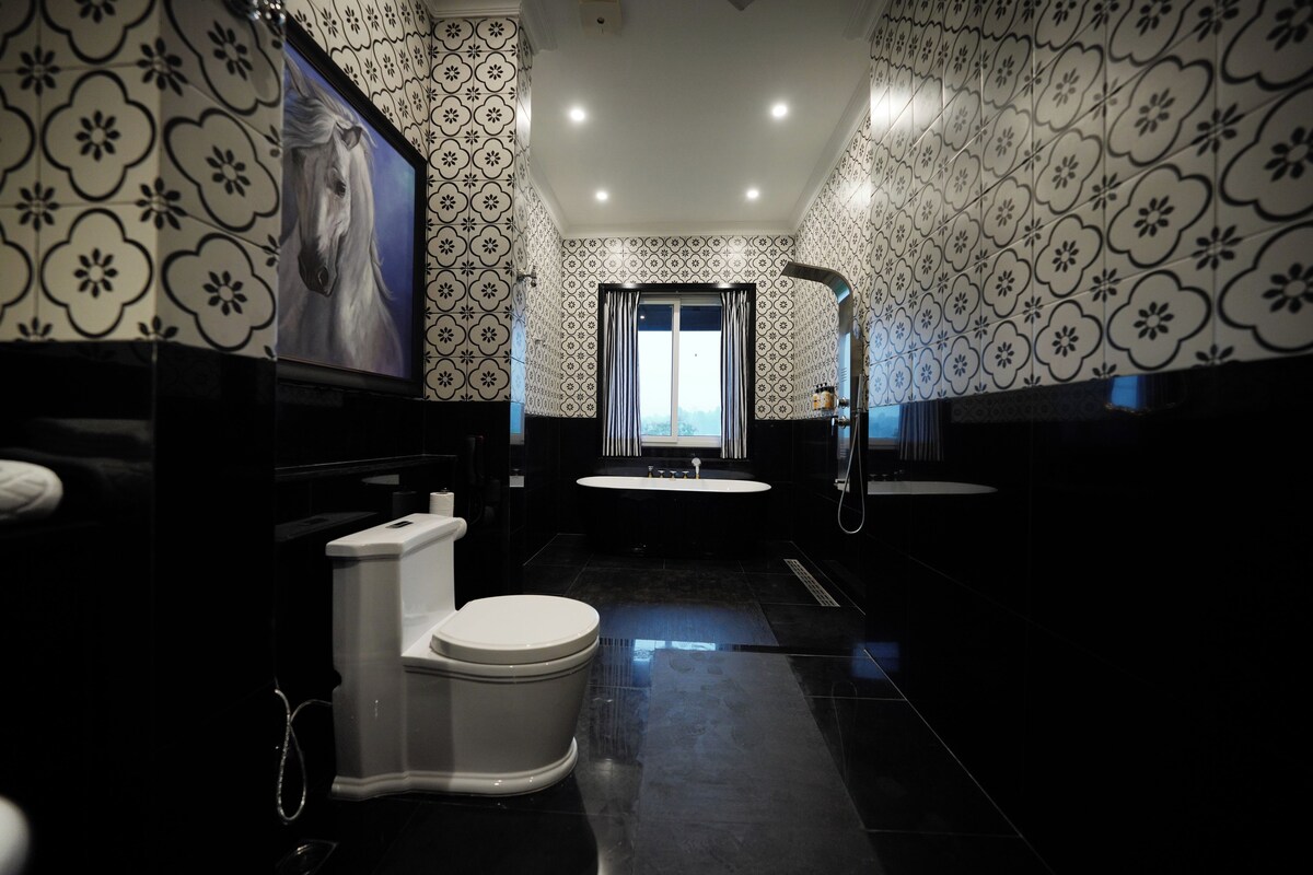 Un baño moderno con inodoro, lavabo y ducha. Las paredes presentan un diseño de baldosas con motivos.