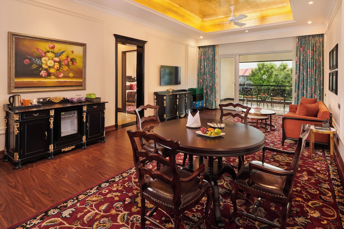 A dining area with a round table, chairs, a buffet, and a painting on the wall.