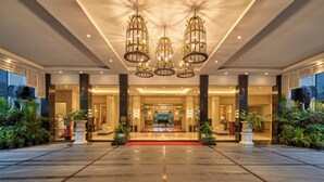 A spacious lobby with a red carpet, large columns, and a chandelier. - Mayfair Tea Resort Siliguri (Siliguri)