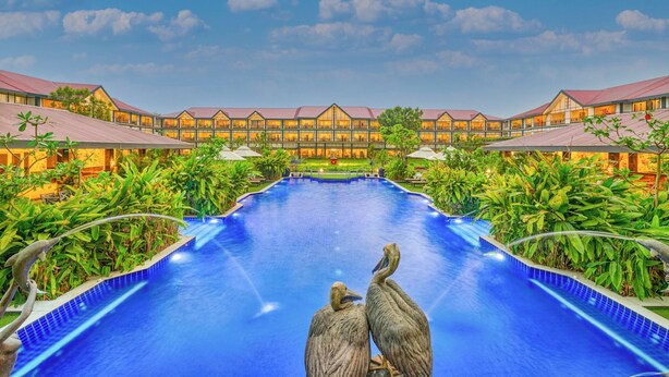 A hotel with a large swimming pool, multiple guest rooms, and lush greenery. - Mayfair Tea Resort Siliguri (Siliguri)