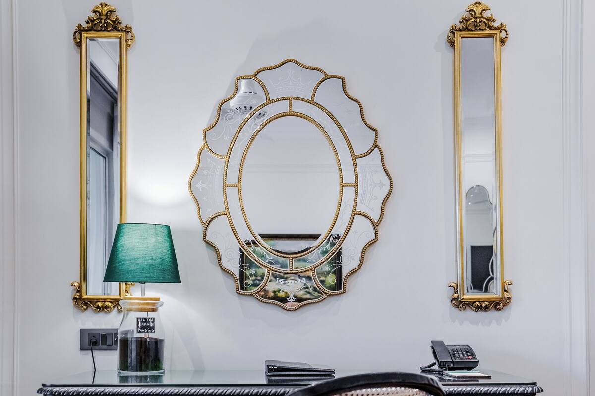 A room with a black desk, a chair, a mirror, and a lamp.