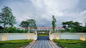 A hotel entrance with a paved pathway leading to a building with a red roof. - Mayfair Tea Resort Siliguri (Siliguri)
